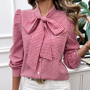 Person wearing a red and white checkered blouse with a bow tie and white pants.