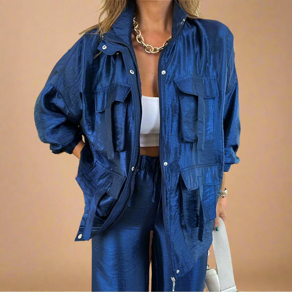 Person wearing a blue textured jacket and pants with a white top indoors.