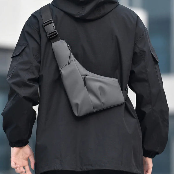 Person wearing a black jacket with a gray crossbody bag on a blurred background