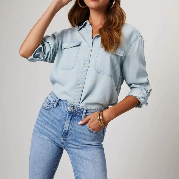 Person wearing a light blue denim shirt and jeans on a plain background