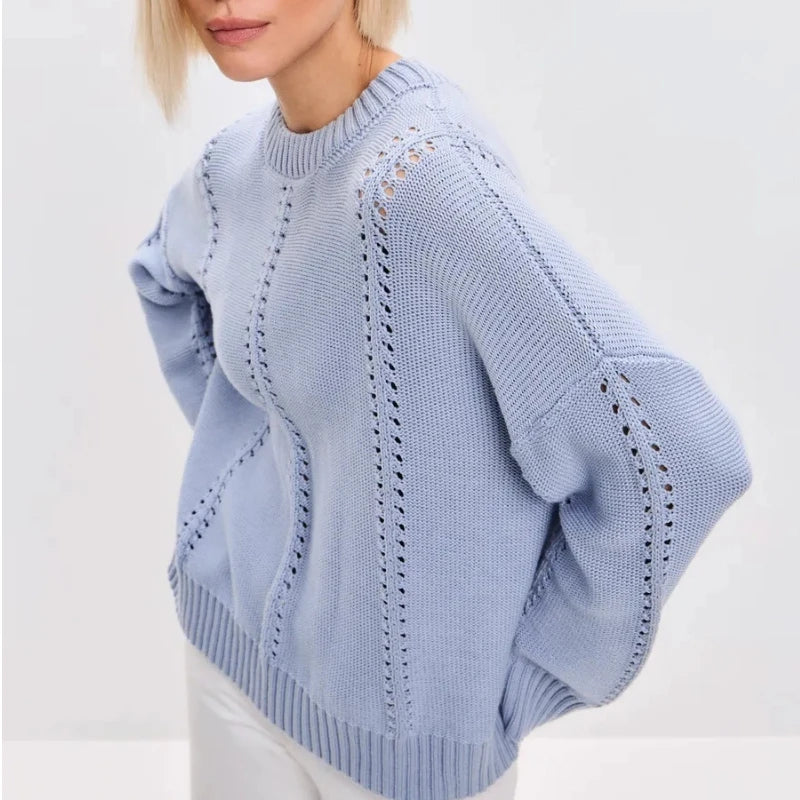 Woman wearing a gray sweater sitting on a white chair against a light gray background