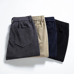 Four pairs of pants in different colors arranged on a light gray background