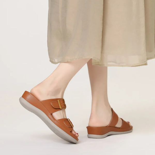 Brown sandals worn with a beige skirt on a light background