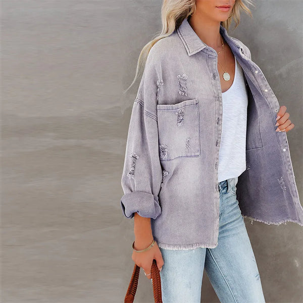 Person wearing a light gray distressed denim jacket over a white shirt with a blurred background