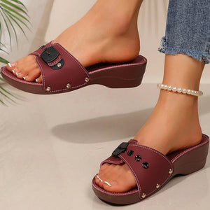 Maroon sandals with black straps worn by a person on a neutral background