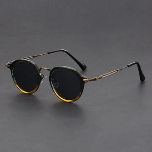 Round sunglasses with gold frame and dark lenses on a gray background