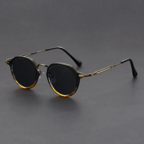 Round sunglasses with gold frame and dark lenses on a gray background