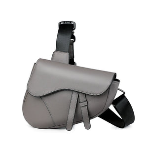 Gray leather saddle bag with a black strap on a white background