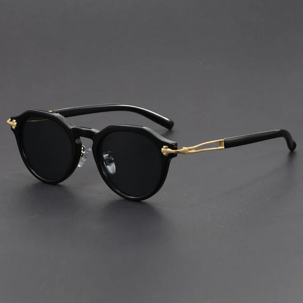 Black sunglasses with gold accents on a dark gray background