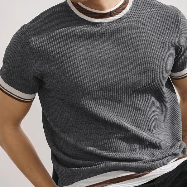 Person wearing a gray ribbed sweater with white and brown stripes on a light background