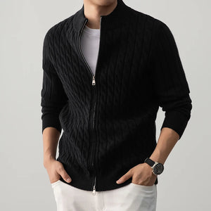 Person wearing a black cable knit jacket on a gray background