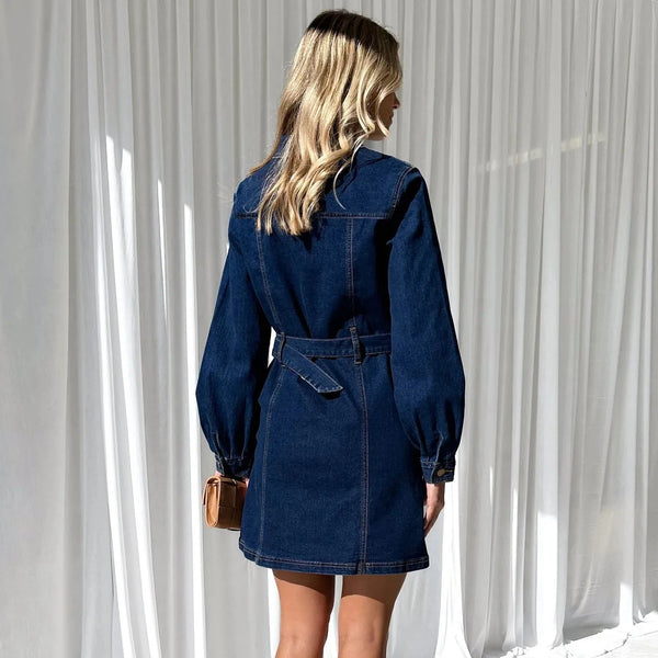 Woman wearing a blue denim dress against a white curtain background