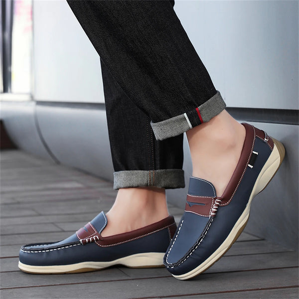 Person wearing blue loafers with brown accents on a wooden floor.