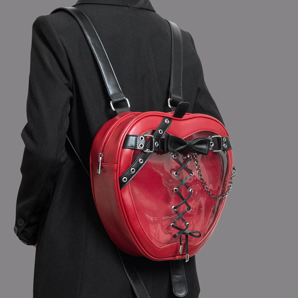 Person wearing a red heart-shaped backpack with black straps on a gray background