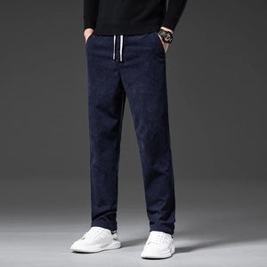 Person wearing navy blue pants with white shoes on a gray background