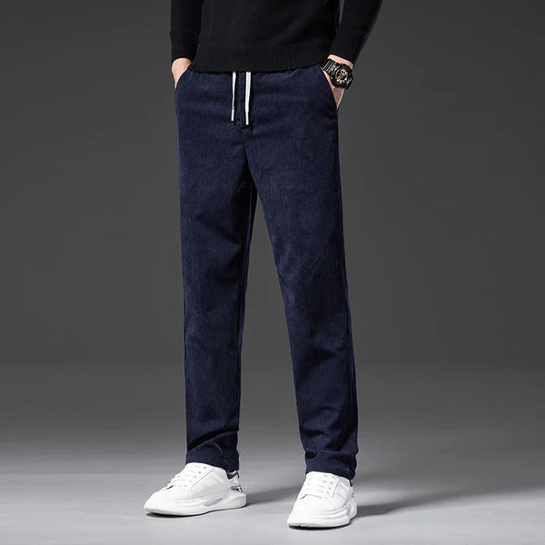Person wearing navy blue pants with white shoes on a gray background