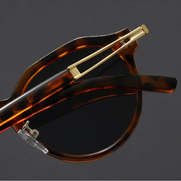 Sunglasses with tortoiseshell frame and gold accents on a dark background