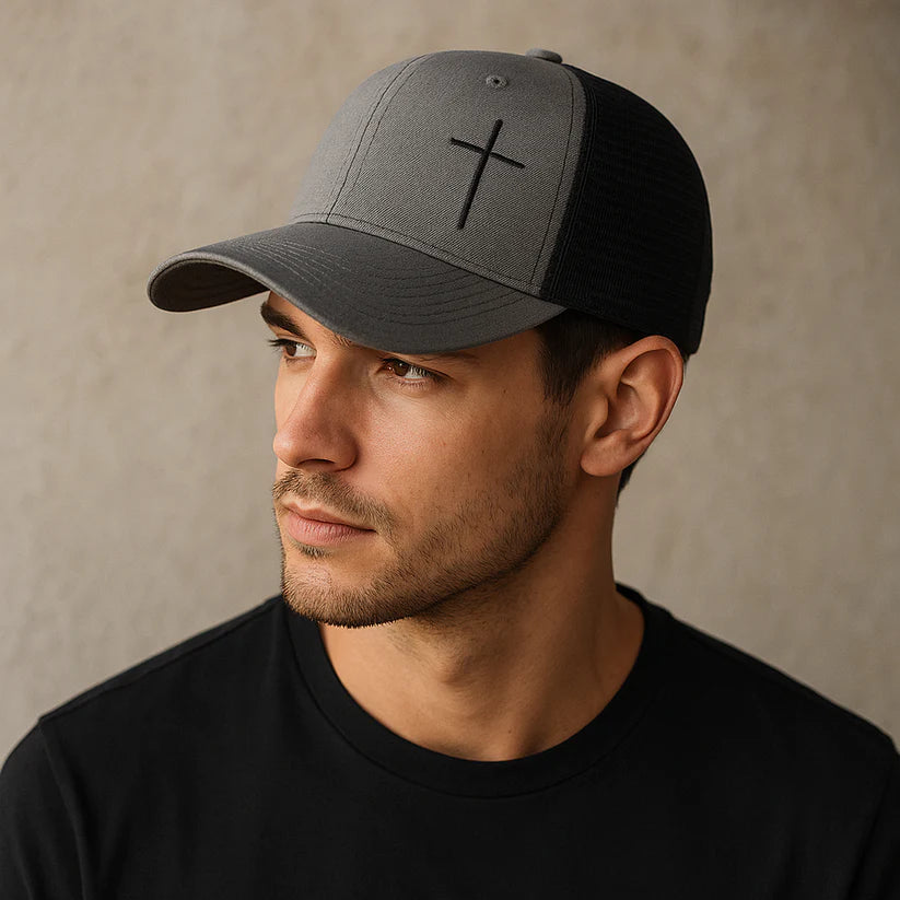 Man wearing a two-tone cap with a cross design on a neutral background