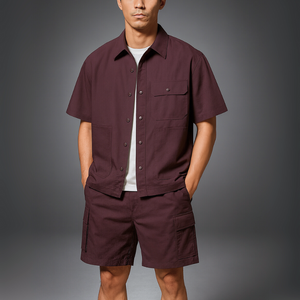 Man wearing a maroon short-sleeve shirt and shorts on a gray background
