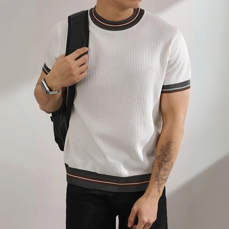Person wearing a gray short-sleeve sweater with white stripes and black pants, standing against a plain background.