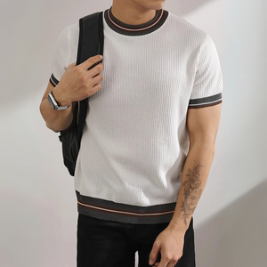 Person wearing a white ribbed sweater with black trim against a plain background