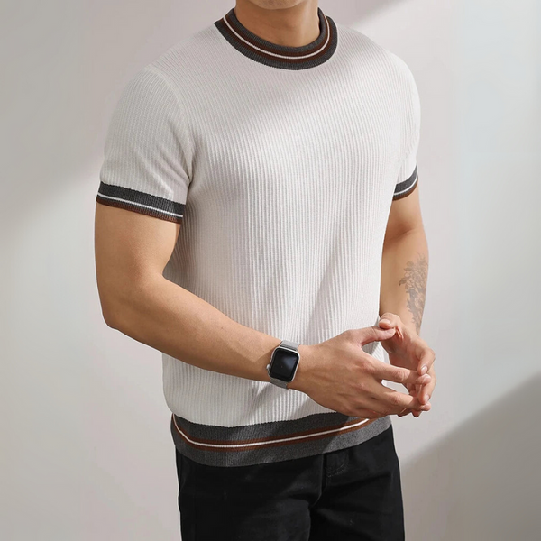 Person wearing a white ribbed knit t-shirt with black and brown trim on a plain background