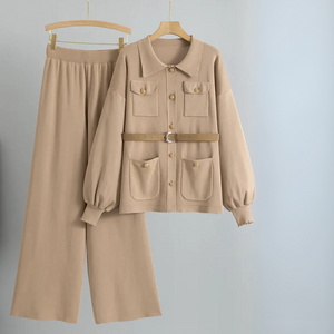 Beige outfit with jacket and pants on hangers against a light gray background