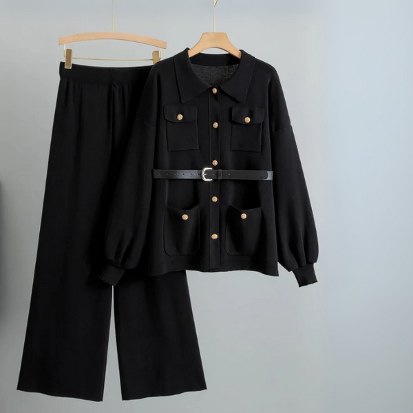 Black outfit with jacket and pants on hangers against a gray background