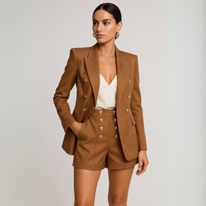 Woman wearing a brown suit with gold buttons on a plain background