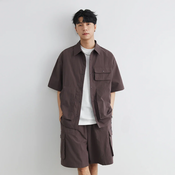 Man wearing a brown shirt and shorts set against a plain background