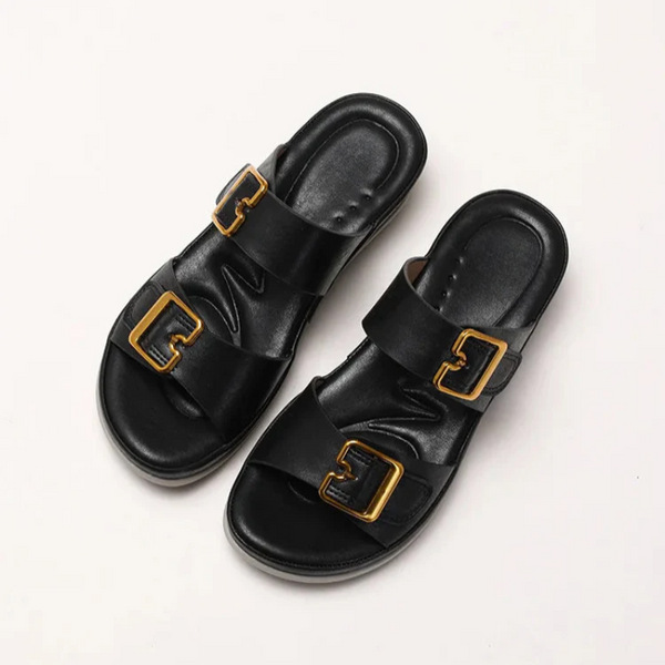 Black sandals with gold buckles on a white background