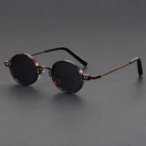 Round sunglasses with brown frame and dark lenses on a gray background