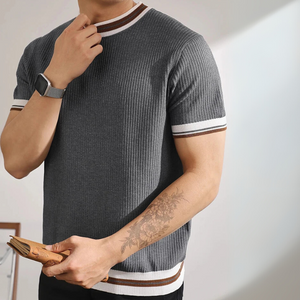 Man wearing a gray ribbed sweater with white and brown stripes, holding a book.