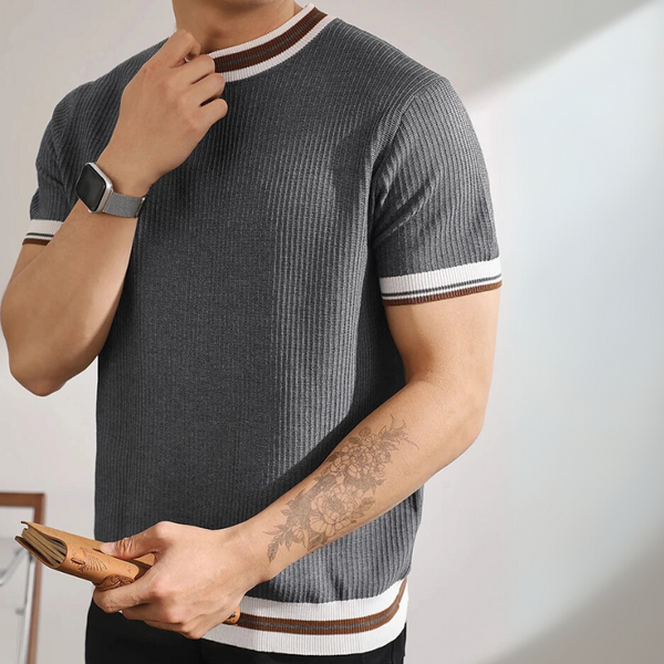 Man wearing a gray ribbed sweater with white and brown stripes, holding a book.