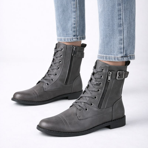 Gray combat boots with zippers worn with light blue jeans on a white background